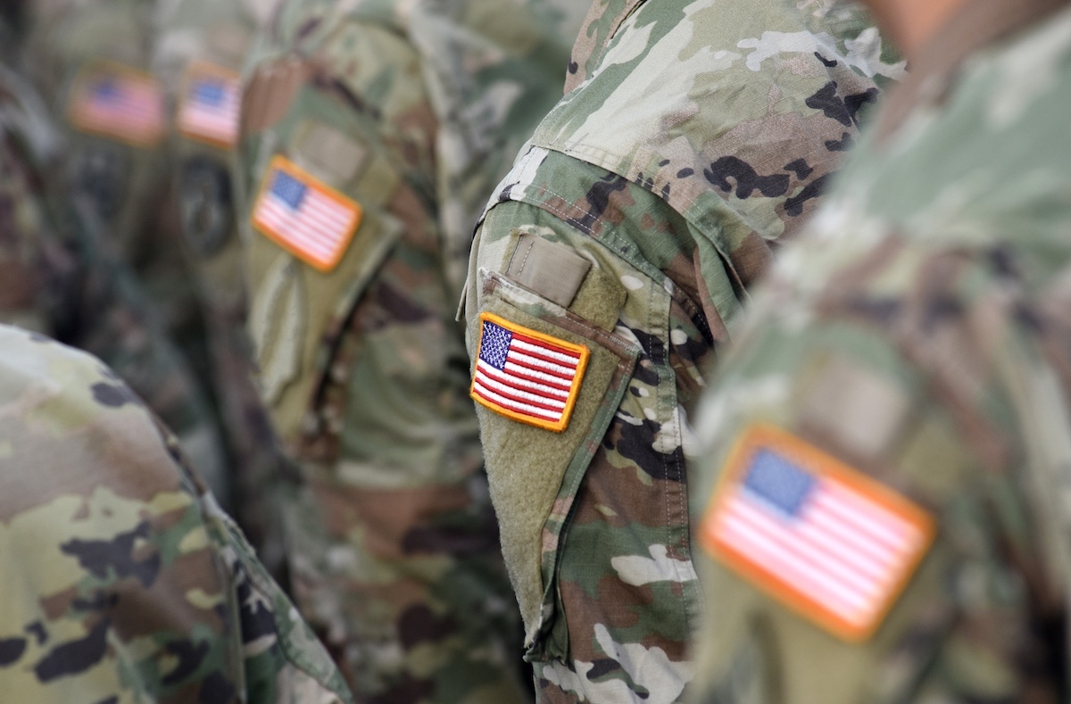 Soldiers in camouflage uniforms with American flag patches on their sleeves.